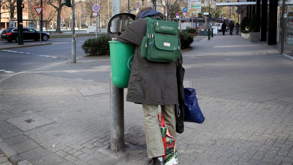 Ein Mann sucht in der Düsseldorfer Innenstadt in einem Mülleimer nach Verwertbarem. Foto: Martin Gerten