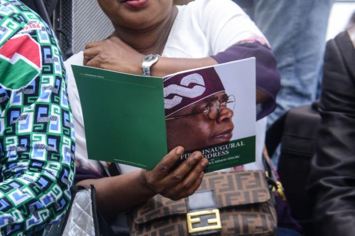 زنی به یک کتابچه رسمی نگاه می کند که چهره بولا تینوبو را در مراسم تحلیف او در ابوجا، نیجریه نشان می دهد - دوشنبه 29 مه 2023