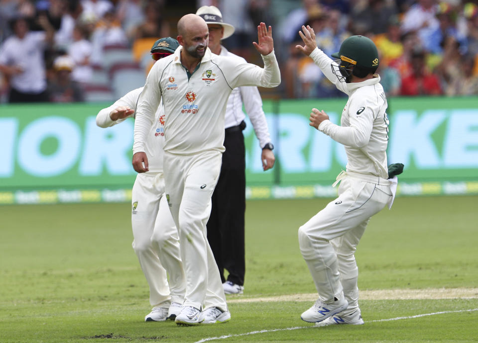 Australia's Nathan Lyon, left, is congratulated by teammate Matthew Wade after taking the wicket of India's Rohit Sharma during play on day two of the fourth cricket test between India and Australia at the Gabba, Brisbane, Australia, Saturday, Jan. 16, 2021. (AP Photo/Tertius Pickard)