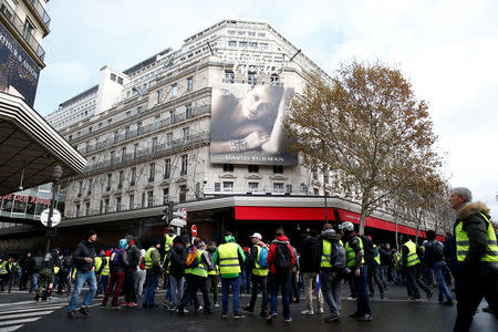 Protesters wearing yellow vests and demonstrators walk past the Galeries Lafayette Department Store during a demonstration as part a national day of protest by the "yellow vests" movement in Paris, France, December 8, 2018. REUTERS/Stephane Mahe