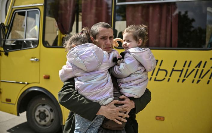 Dmytro Mosur, 32, who lost his wife during shelling in nearby Severodonetsk on May 17, holds his two-year-old twin daughters as they wait to be evacuated from the city of Lysychansk, eastern Ukraine - AFP