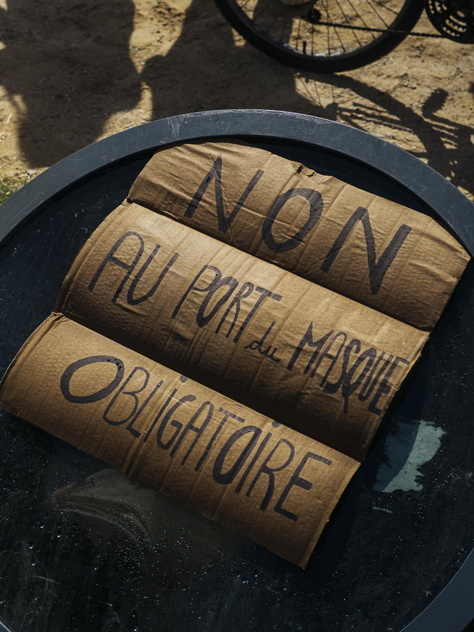 A sign that reads: "No to mandatory mask wearing", is seen on the ground during an anti-mask demonstration in Paris, Saturday, Aug. 29, 2020. A few hundred people rallied Saturday at the Place de la Nation in eastern Paris to protest new mask rules and other restrictions prompted by rising virus infections around France. (AP Photo/Kamil Zihnioglu)