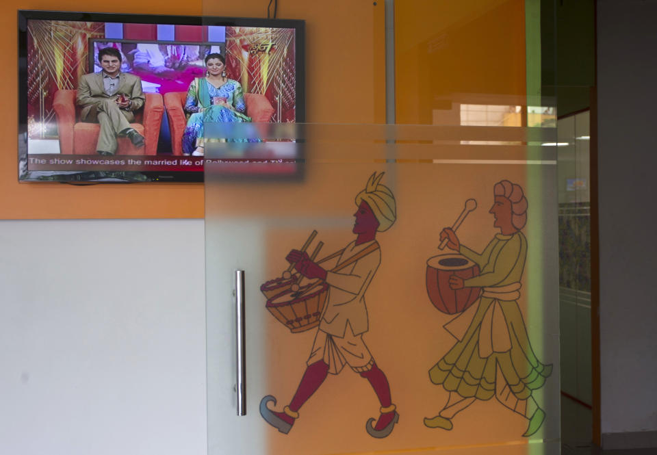 In this July 26, 2013 photo, a talk show episode is displayed on a television at the entrance of the Shagun TV studio in Noida, India. Indians are obsessed with weddings and obsessed with reality television. Now Shagun TV, a new television channel headquartered in a sprawling suburb of India's capital, is hoping it has found a can't-miss idea — merging the two into a 24-hour matrimonial TV station.(AP Photo/Tsering Topgyal)