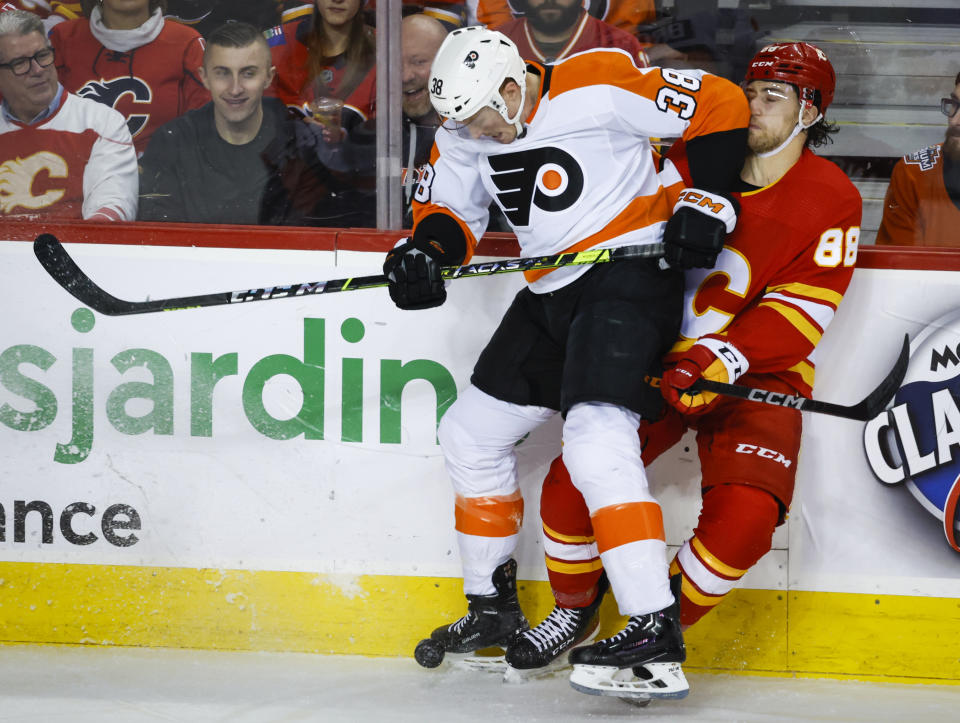 Philadelphia Flyers forward Patrick Brown, left, checks Calgary Flames forward Andrew Mangiapane during the first period of an NHL hockey game in Calgary, Alberta, Monday, Feb. 20, 2023. (Jeff McIntosh/The Canadian Press via AP)