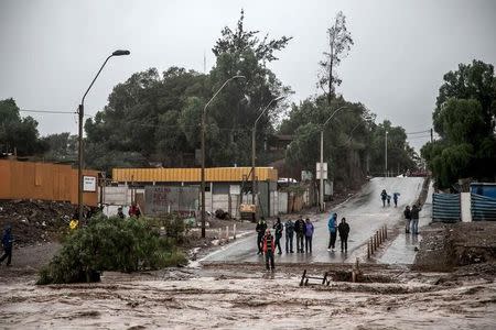 Locals gather near a flooded road after heavy rains in Copiapo city, March 25, 2015. REUTERS/Stringer
