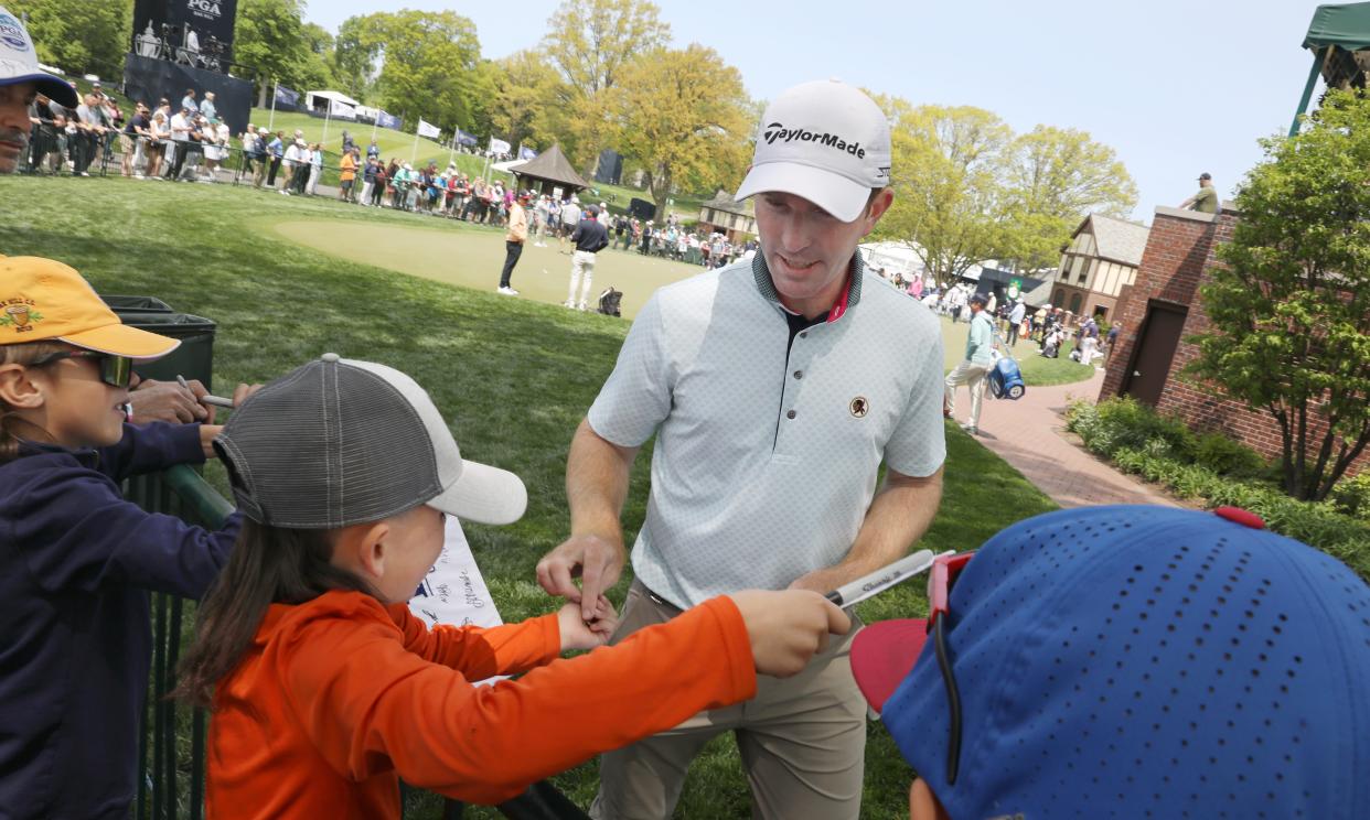 Matt Cahill hands out ball markers to kids lining the practice putting green before heading out for his practice round at the PGA Championship at Oak Hill Country Club.