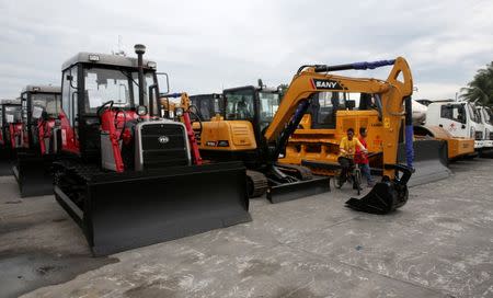 A port worker rides his bike in front of construction equipment donated by China, that will aid in the rehabilitation of the war-torn Marawi city, in the port of Iligan city, southern Philippines October 19, 2017. REUTERS/Romeo Ranoco