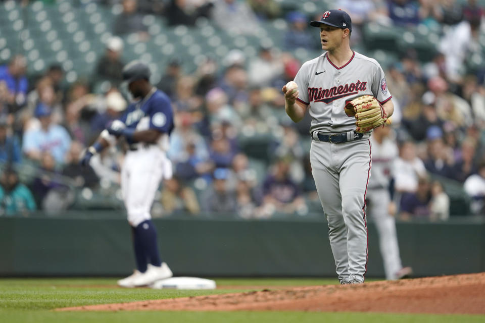 Minnesota Twins starting pitcher Sonny Gray, right, holds the baseball after Seattle Mariners' Taylor Trammell, left, reached third base after hitting a double and an outfield throwing error during the third inning of a baseball game, Wednesday, June 15, 2022, in Seattle. (AP Photo/Ted S. Warren)