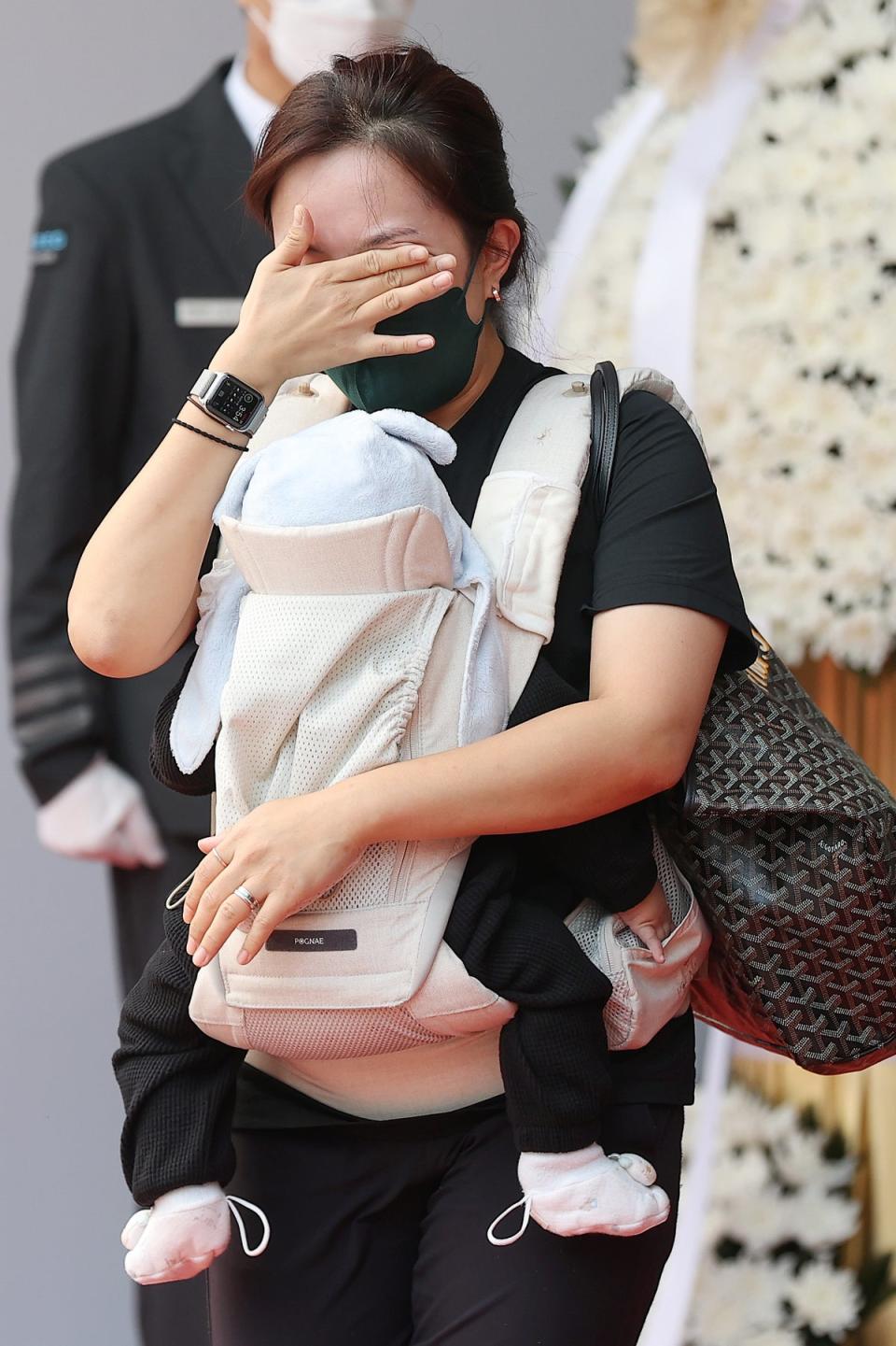 A woman carrying a baby cries at a memorial altar to the victims of a deadly stampede in Seoul (EPA)