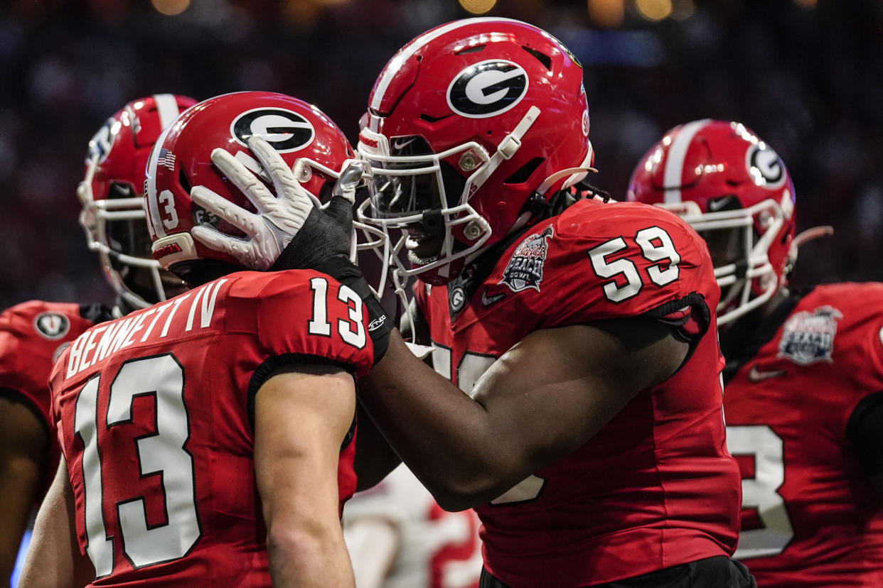 Georgia quarterback Stetson Bennett (13) celebrates his touchdown run with Georgia offensive lineman Broderick Jones (59) during the first half of the Peach Bowl NCAA college football semifinal playoff game against Ohio State, Saturday, Dec. 31, 2022, in Atlanta. (AP Photo/Brynn Anderson)