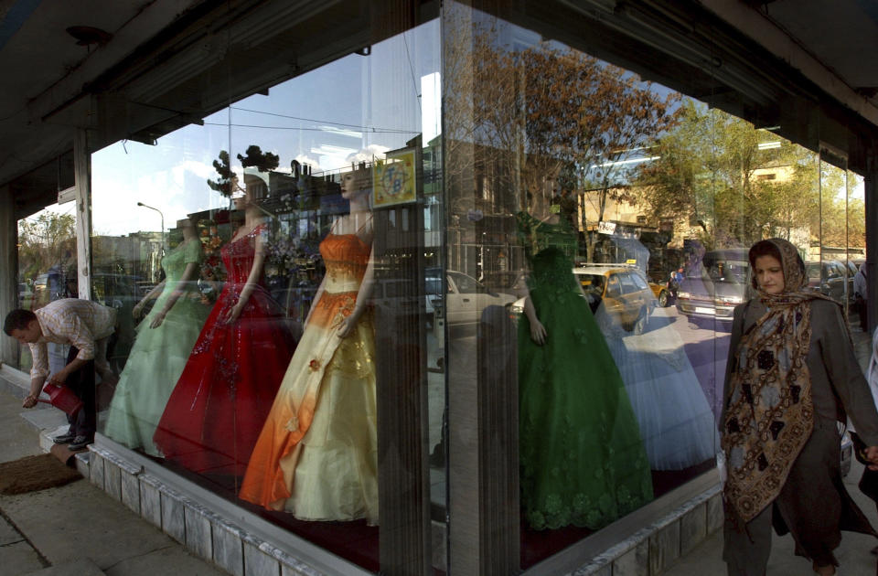 FILE -- In this June 15, 2006 file photo, an Afghan woman walks past modern dresses in Kabul, Afghanistan. The Taliban fighters who rolled into Afghanistan's capital and other cities in recent days appear awestruck by the towering apartment blocks, modern office buildings and shopping malls. When the Taliban last seized power, in 1996, the country had been ravaged by civil war and the capital was in ruins. (AP Photo/Musadeq Sadeq, File)