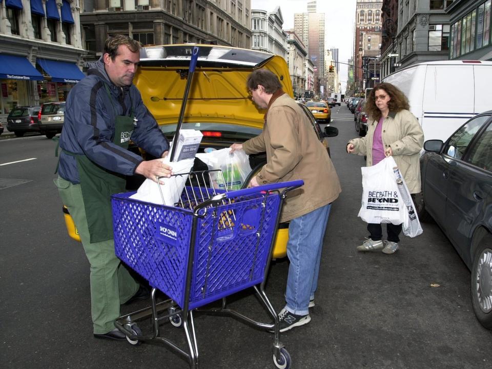 Bed Bath & Beyond employee helps customers load their purchases into the trunk of a taxi