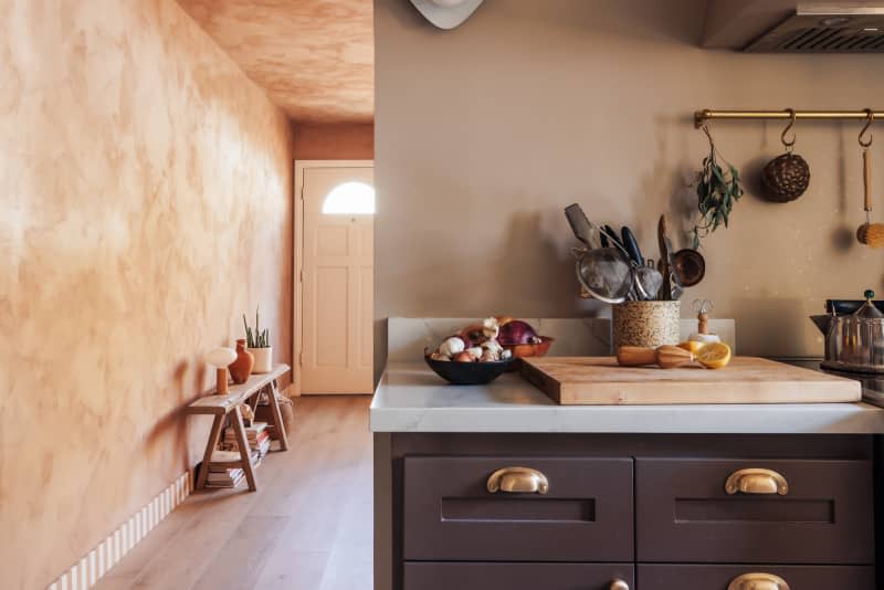 Beige kitchen with textured walls and deep blue cabinets and appliances with view into entryway area