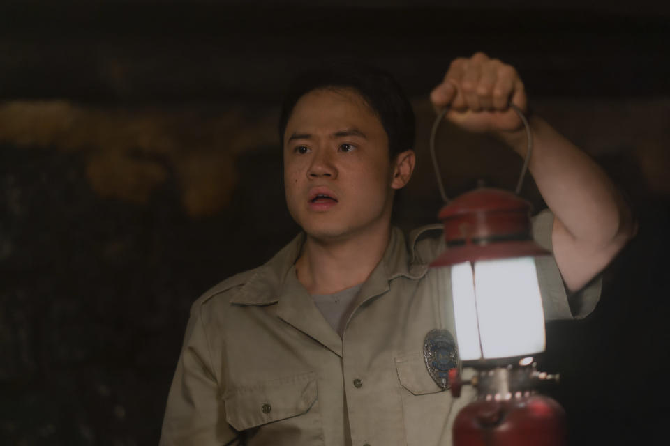 Ricky He raises a lantern in a dark cavern
