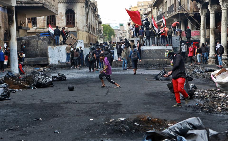 Anti-government protesters gather near barriers set up by security forces to close Rasheed Street during ongoing protests in Baghdad, Iraq, Tuesday, Dec. 3, 2019. At least 400 people have died since the leaderless uprising shook Iraq on Oct. 1, with thousands of Iraqis taking to the streets in Baghdad and the predominantly Shiite southern Iraq decrying corruption, poor services, lack of jobs and calling for an end to the political system that was imposed after the 2003 U.S. invasion. (AP Photo/Khalid Mohammed)