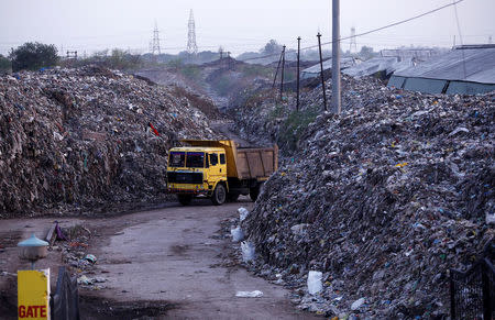 Smoke billows as a truck drives past the waste of leather tanneries at a dumpyard in Kanpur, India, May 3, 2018. Picture taken May 3, 2018. REUTERS/Adnan Abidi