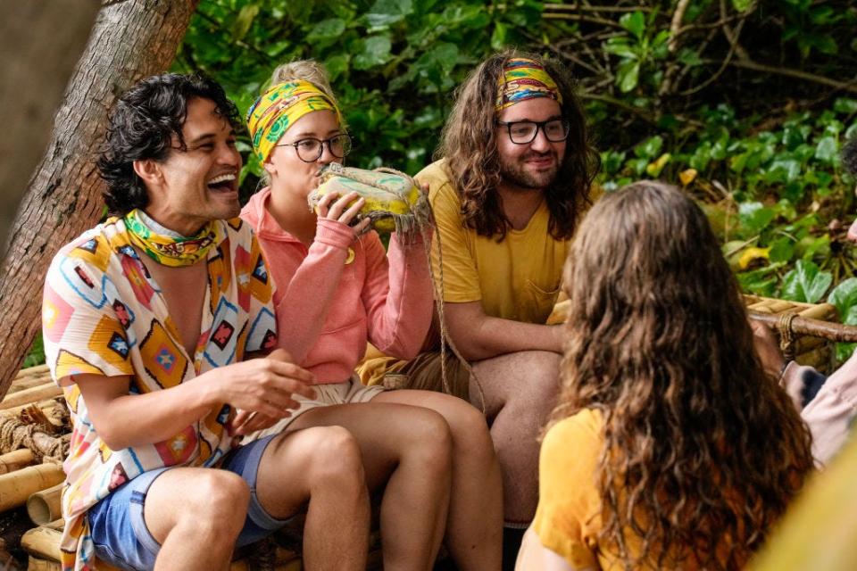 "Survivor" contestants from season 45 sitting on a log and talking together