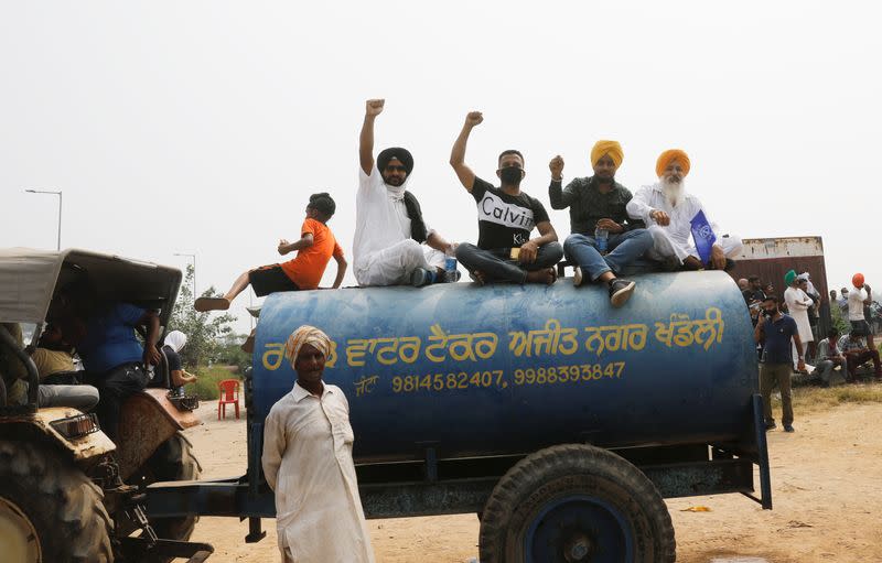 Farmers sit on the water tank as they block a national highway during a protest against farm bills passed by India's parliament, in Shambhu