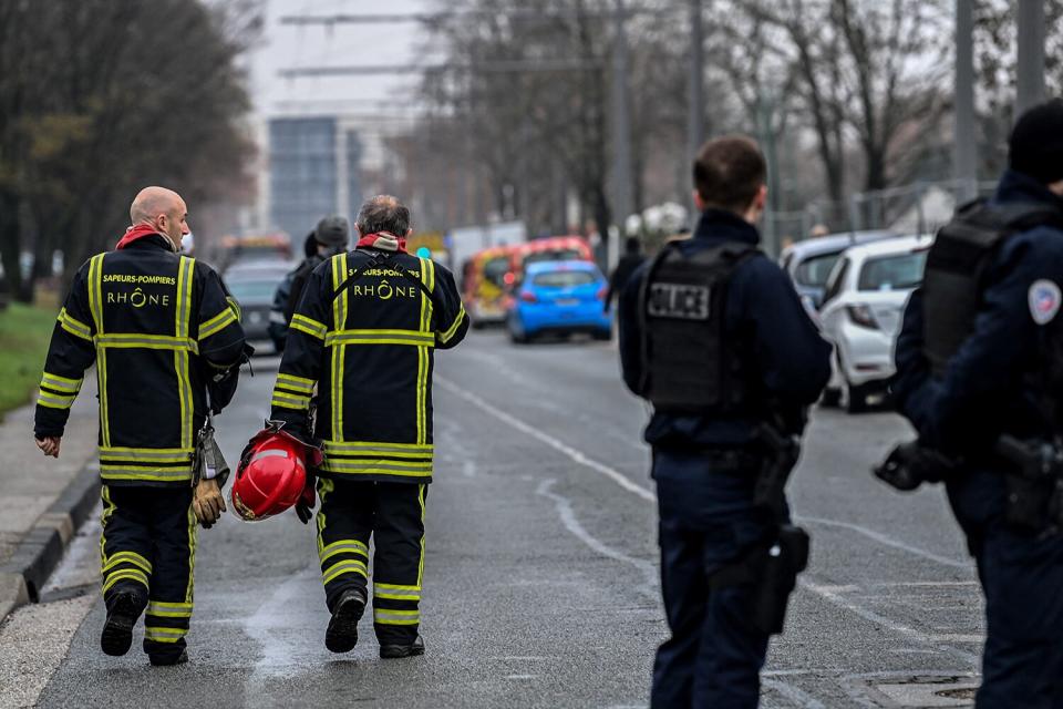 Policemen guard a security perimeter as firefighters and rescuers work outside a seven-storey apartment building where five children including a three-year-old were among 10 people killed when a fire broke out in the Mas-Du-Taureau neighbourhood of Vaulx-en-Velin, in the northern outskirts of Lyon, on December 16, 2022