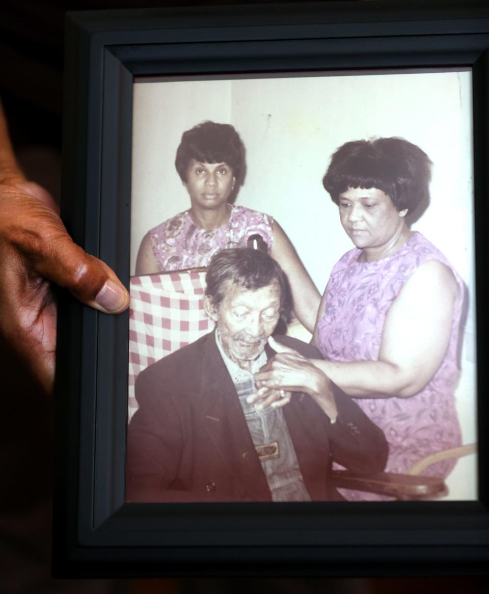 Ora Jackson, 99, holds a photo showing her father Virge Cooley when he was elderly. A young Ora is seen standing behind her seated father. To her right is one of her sisters, Elsie.