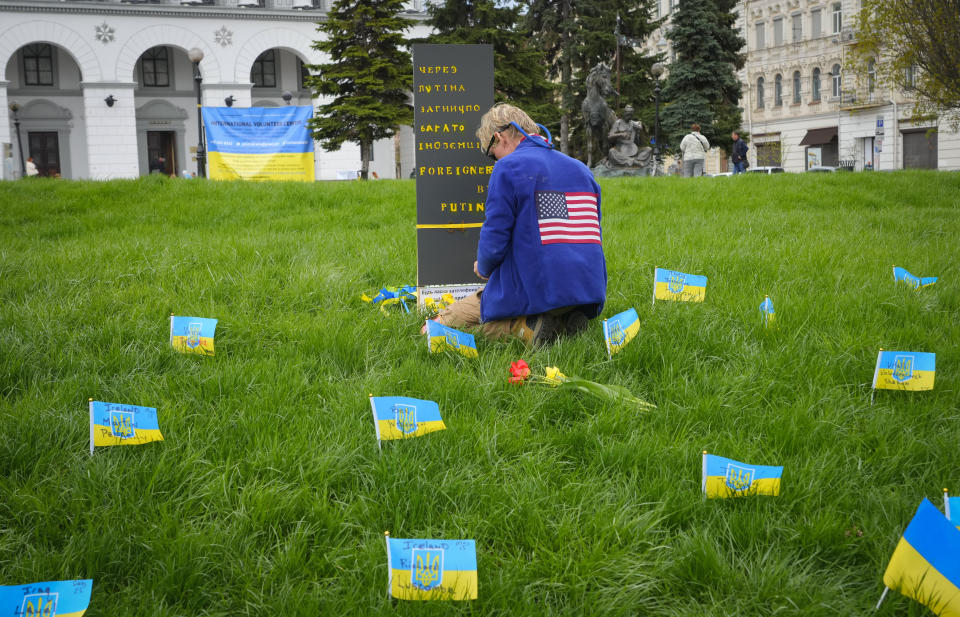 A man pays tribute to foreign citizens killed during Russia-Ukraine war near a memorial sign reading "Foreigners killed by Putin" in a central square in Kyiv, Ukraine, Saturday, Apr. 30, 2022. Names of the killed foreigners are written on the Ukrainian flags. (AP Photo/Efrem Lukatsky)