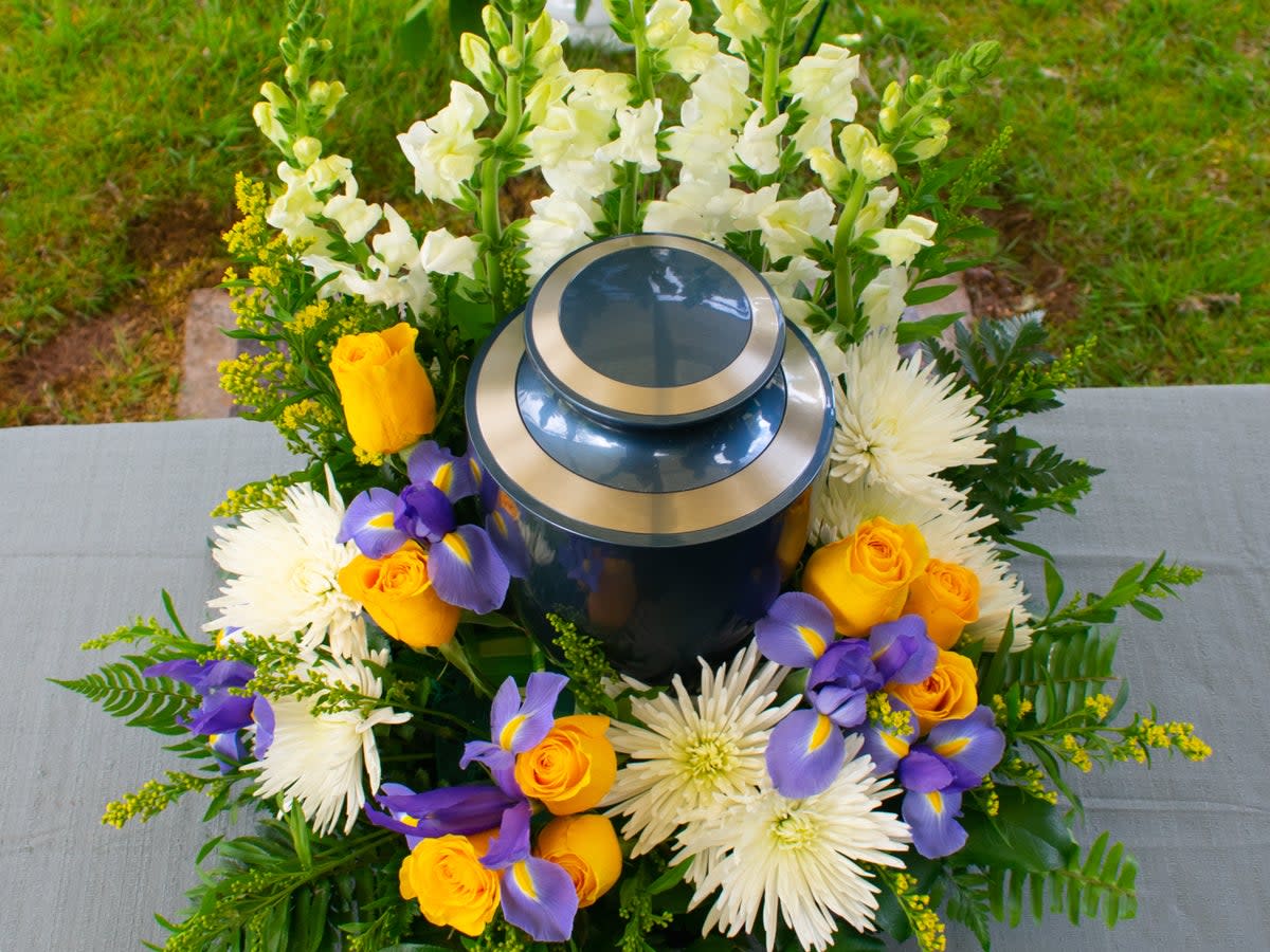 A cremation urn  with floral arrangement at a funeral ceremony (Getty/iStock)