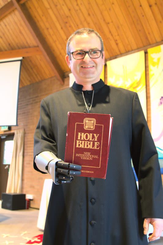Priest-in-training Daniel Cant holds a bible as he demonstrates his bionic arm by British company Open Bionics at Christ Church in Colchester