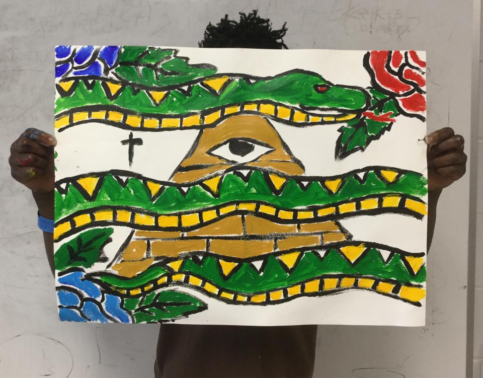A male teen in a Cathedral Arts Project visual arts program at the John E. Goode Pre-Trial Detention Facility in Jacksonville displays his painting.