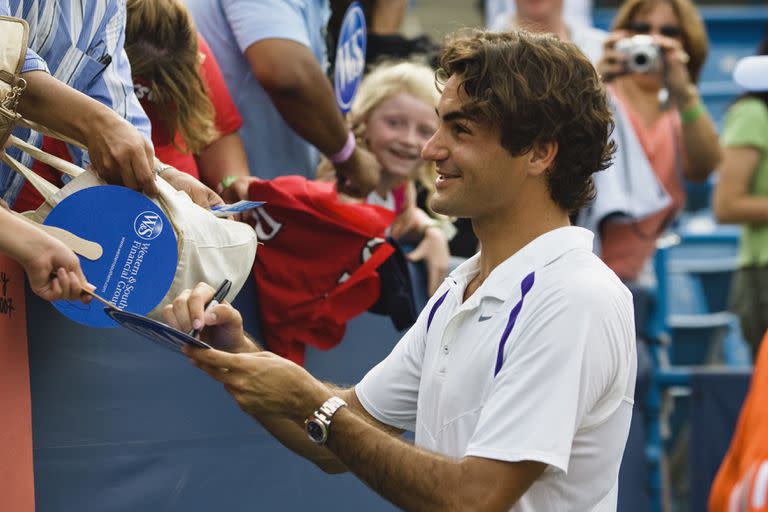 Un sonriente Roger Federer firma autógrafos de sus muchos fanáticos después de su 50º título ATP de su carrera después de derrotar a James Blake (EE. UU.) en el partido de campeonato en el torneo de tenis Masters ATP del Western and Southern Financial Group en Cincinnati. Federer vence a James Blake 6-1, 6-4 para ganar el torneo y ganar el título ATP número 50 de su carrera. Federer se convierte en el quinto jugador más joven en lograr este hito.