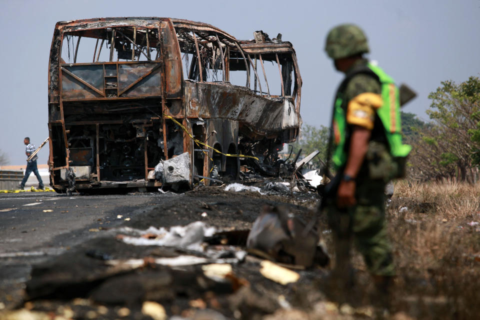 CORRECTS SPELLING OF PHOTOGRAPHER'S FIRST NAME - A soldier guards the site where a passenger bus slammed into a broken-down truck and burst into flames near the town of Ciudad Isla in the Gulf state of Veracruz, Mexico, Sunday, April 13, 2014. Dozens of people traveling on the bus to Mexico City burned to death inside the bus. (AP Photo/Felix Marquez)