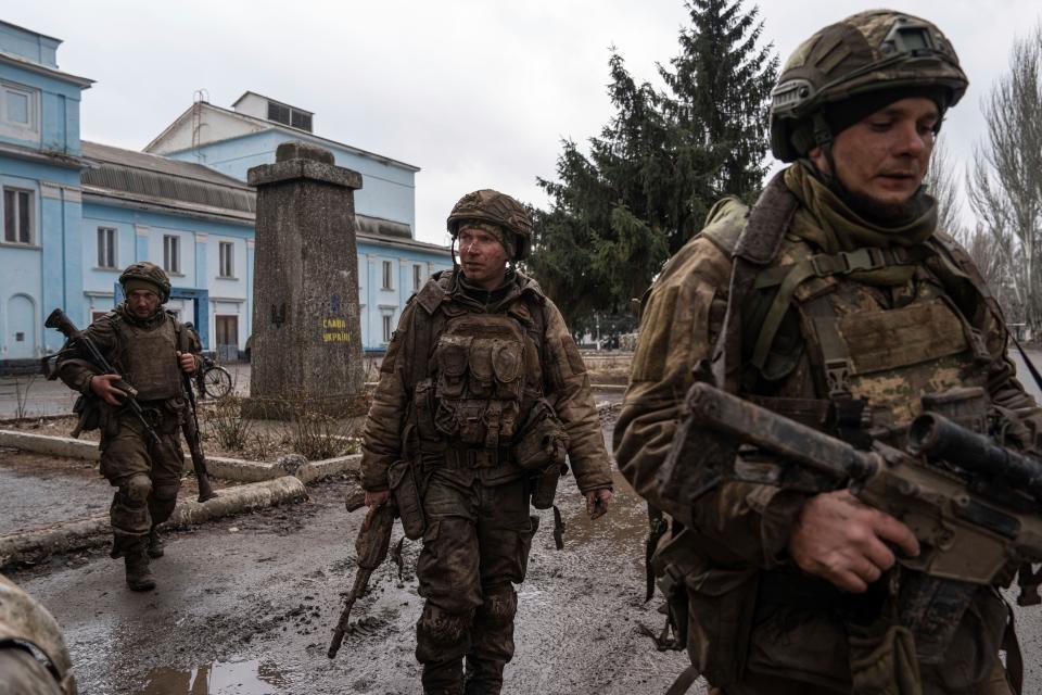 Ukrainian servicemen who recently returned from the trenches of Bakhmut walk on a street in Chasiv Yar March 8. (Evgeniy Maloletka/AP)