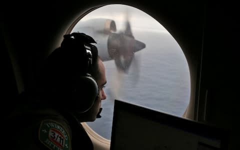 Rayan Gharazeddine scans the water in the southern Indian Ocean off Australia from a Royal Australian Air Force AP-3C Orion during a search for the missing plane in 2014 - Credit: Rob Griffith/AP