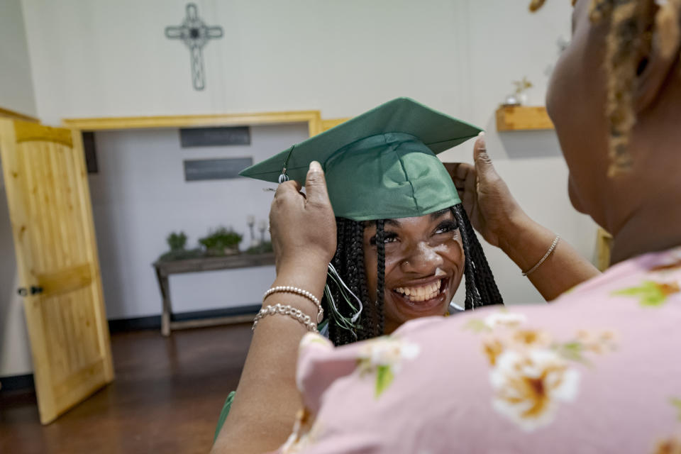 Kanotaye Rodgers, right, adjusts the mortar cap of graduate Chloy'e Polite, 19, before a graduation ceremony for Springfield Preparatory School at Victory in Christ church in Holden, La., Saturday, Aug. 5, 2023. Nearly 9,000 private schools in Louisiana don’t need state approval to grant degrees. Non-approved schools make up a small percentage of the state total. But the students in Louisiana’s off-the-grid school system are a rapidly growing example of the national fallout from COVID-19 — families disengaging from traditional education. (AP Photo/Matthew Hinton)