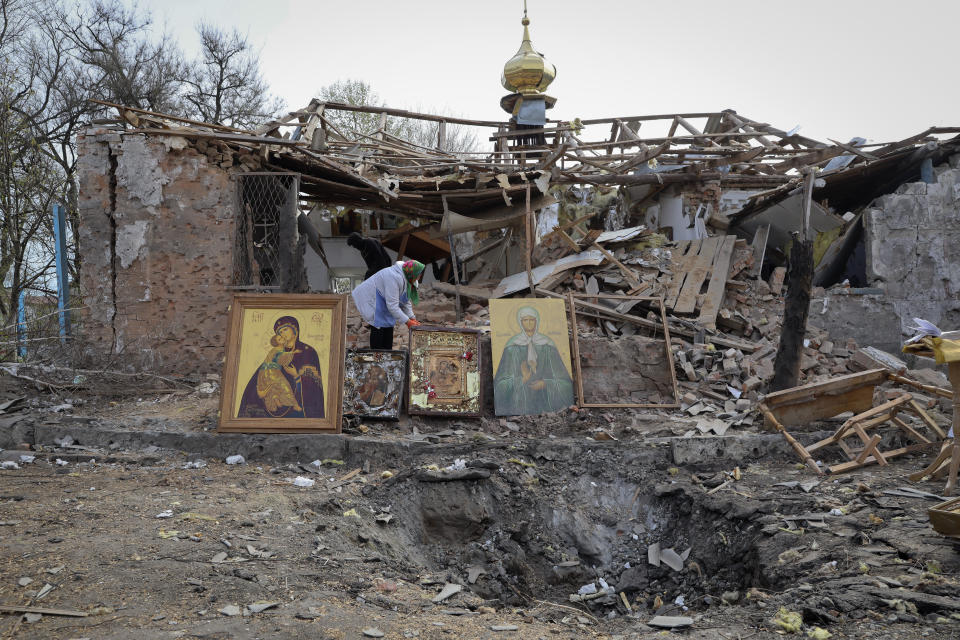 CAPTION CORRECTS TOWN SPELLING - People save icons as they clear the rubble after a Russian rocket ruined an Orthodox church in rocket attack on Easter night, a crater left by the rocket in the foreground, in Komyshuvakha, Zaporizhzhia region, Ukraine, early hours Sunday, April 16, 2023. (AP Photo/Kateryna Klochko)