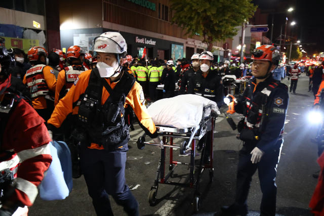 Emergency services workers pull a stretcher in a city street.