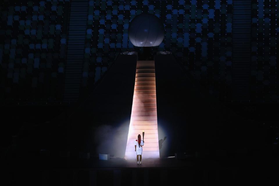 Naomi Osaka of Team Japan carries the Olympic torch towards the Olympic cauldron during the opening ceremony.