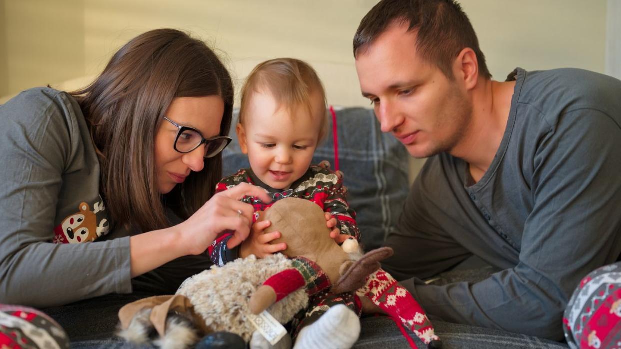 young couple in christmas pajamas playing with their lovely baby