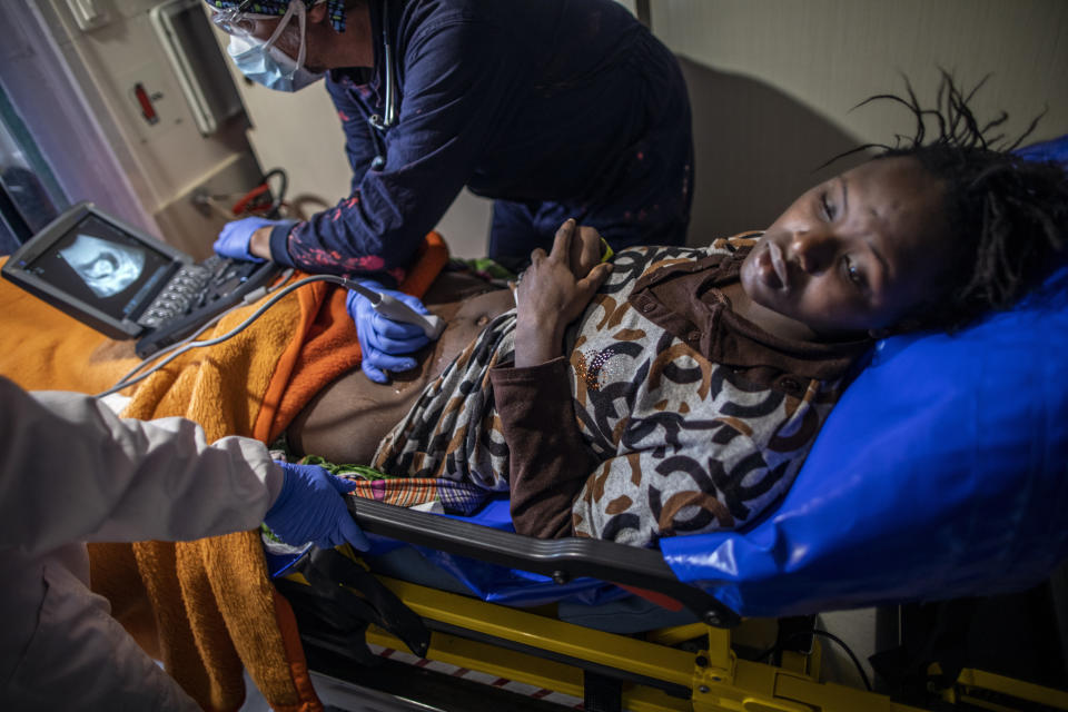 Sita Yakita, de 16 años y natural de Guinea Conakry, descansa en la enfermería mientras Juanfe, el doctor a bordo del buque de la ONG española Open Arms, le hace una ecografía para ver a su bebé, tras ser rescatada en aguas internacionales del Mar Mediterráneo, el 14 de febrero de 2021. En los últimos días, las autoridades libias han impedido ocho intentos de rescate por parte del Open Arms, el barco de la ONG española del mismo nombre, acosando y amenazando a su tripulación. (AP Foto/Bruno Thevenin)