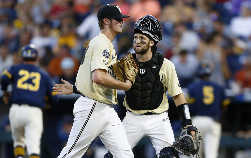 Vanderbilt pitcher Jake Eder, left, is greeted by Philip Clarke during the eighth inning of Game 3 of the NCAA College World Series baseball finals against Michigan in Omaha, Neb., Wednesday, June 26, 2019. (AP Photo/John Peterson)