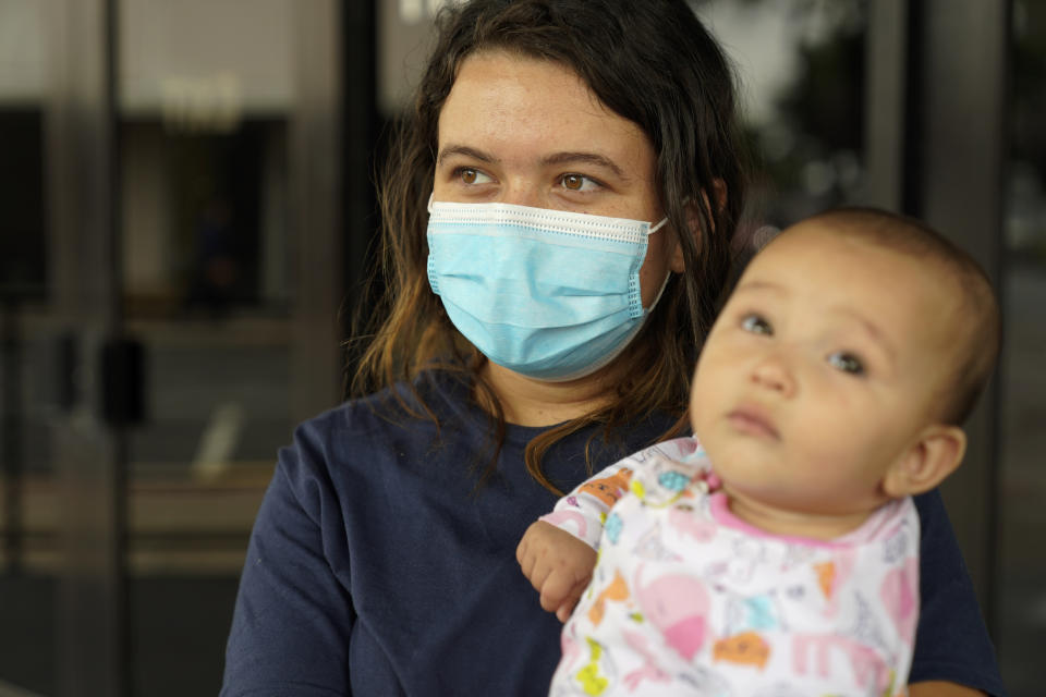 Laura Scalzo, 20, of Honduras, holds her baby as she talks at at shelter for migrants, Wednesday, May 12, 2021, in McAllen, Texas. Scalzo joined hundreds of others journeying north with her 6-month-old baby and turned herself over to immigration agents patrolling a vast area of South Texas. The U.S. government continues to report large numbers of migrants crossing the U.S.-Mexico border with an increase in adult crossers, most who are immediately expelled back into Mexico under a pandemic-related authority granted by the U.S. Centers for Disease Control and Prevention. (AP Photo/Gregory Bull)