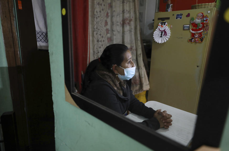 La migrante venezolana Yaquelin Timaure se ve reflejada en un espejo durante una entrevista en su casa en Bogotá, Colombia, el lunes 21 de diciembre de 2020. (AP Foto/Fernando Vergara)