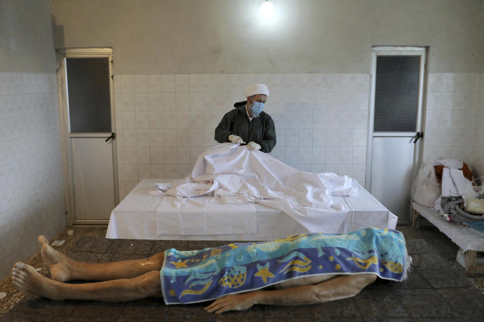 Ali Rahimi, 53, a volunteer cleric wearing protective clothing prepares the body of an 85-year-old man who died from COVID-19 for a funeral at a cemetery in the Chaali village on the outskirts of the city of Ghaemshahr, in northern Iran, Thursday, Dec. 17, 2020. (AP Photo/Ebrahim Noroozi)