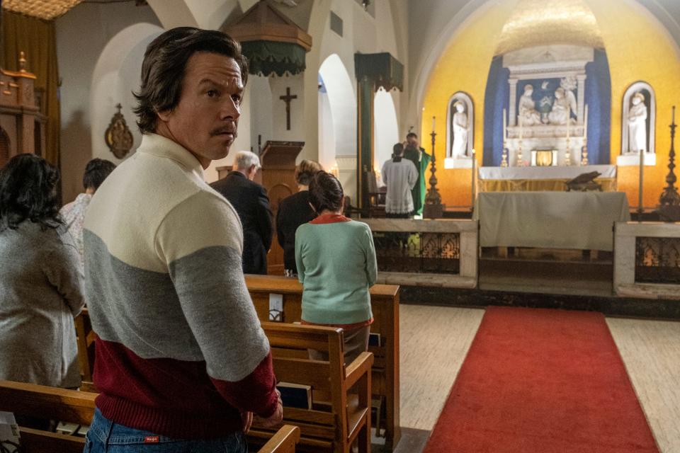 Mark Wahlberg in a sweater and mustache in a church