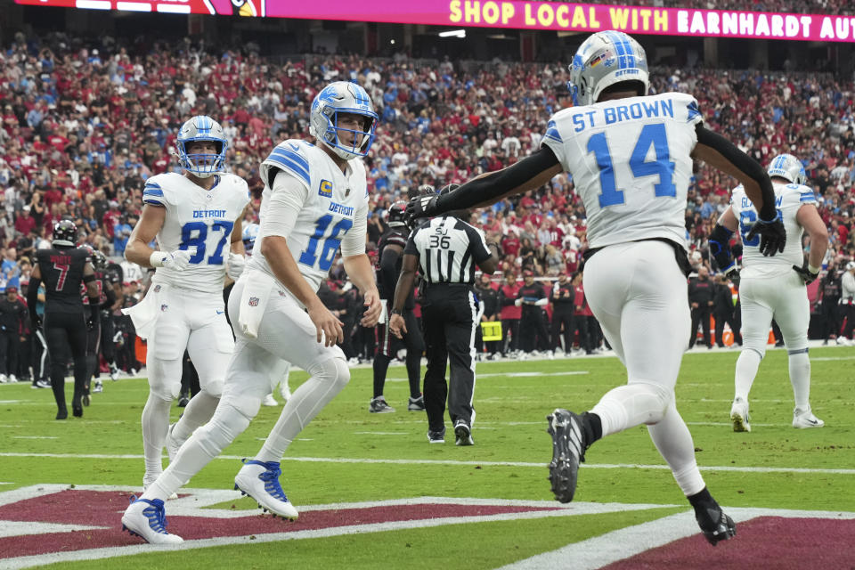 Detroit Lions wide receiver Amon-Ra St. Brown (14) celebrates his five-yard touchdown reception with quarterback Jared Goff (16) during the first half of an NFL football game against the Arizona Cardinals Sunday, Sept. 22, 2024, in Glendale, Ariz. (AP Photo/Rick Scuteri)