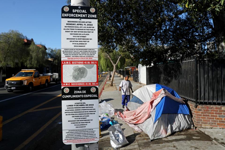 A tent is set up next to signs advising of the camping ban.