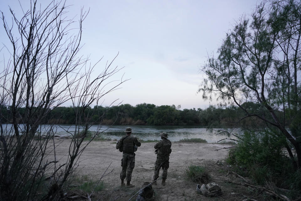 Members of the Texas Military Department stand guard along the U.S.-Mexico border Tuesday, May 11, 2021, in Roma, Texas. The U.S. government continues to report large numbers of migrants crossing the U.S.-Mexico border with an increase in adult crossers. But families and unaccompanied children are still arriving in dramatic numbers despite the weather changing in the Rio Grande Valley registering hotter days and nights. (AP Photo/Gregory Bull)
