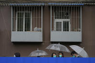 Locked-down residents holding umbrellas line up in the rain for COVID tests outside the apartment building on Wednesday, April 27, 2022, in Beijing. Workers put up fencing and police restricted who could leave a locked-down area in Beijing on Tuesday as authorities in the Chinese capital stepped up efforts to prevent a major COVID-19 outbreak like the one that has all but shut down the city of Shanghai. (AP Photo/Andy Wong)