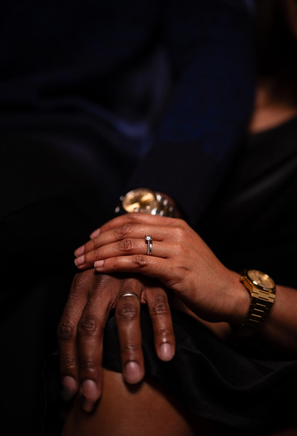 Close-up of two people holding hands, showcasing a wedding ring on one person's finger