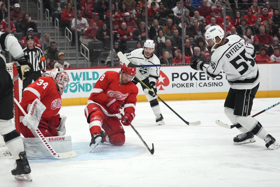 Los Angeles Kings right wing Quinton Byfield (55) scores on Detroit Red Wings goaltender Alex Lyon (34) as Ben Chiarot (8) defends in the first period of an NHL hockey game Saturday, Jan. 13, 2024, in Detroit. (AP Photo/Paul Sancya)