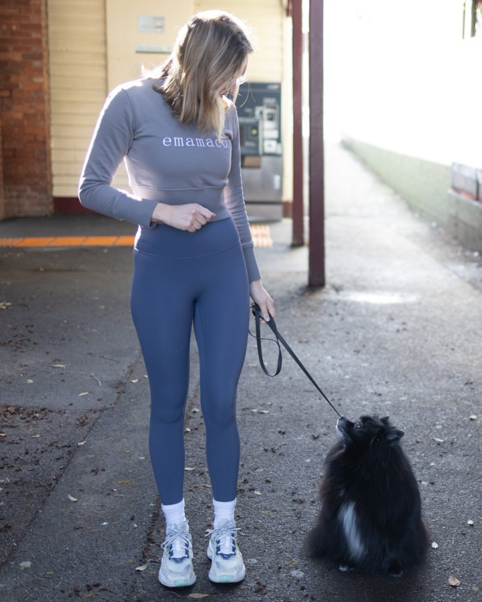 Model wearing fur-repellant leggings from emamaco and walking her small dog.